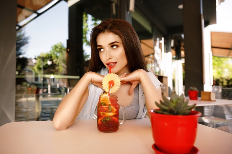 sitting, focus on foreground, beauty, grey tops, young adult, glass, cocktail, adult, front view, drink, indoors, brunette, women outdoors, 1080P, beautiful woman