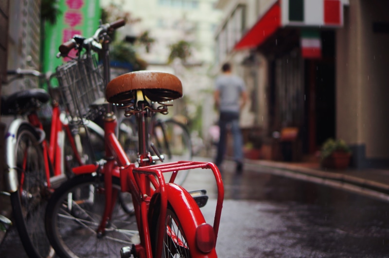 land vehicle, close-up, incidental people, mode of transportation, building exterior, folding, parked, rainy, wheel, built structure, folding bike, focus