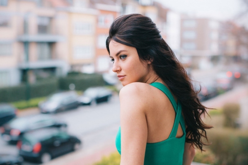 Aurela Skandaj, women, looking over shoulder, face, blue eyes, long hair, outdoors, one person, looking, brunette, brown hair, young adult, architecture