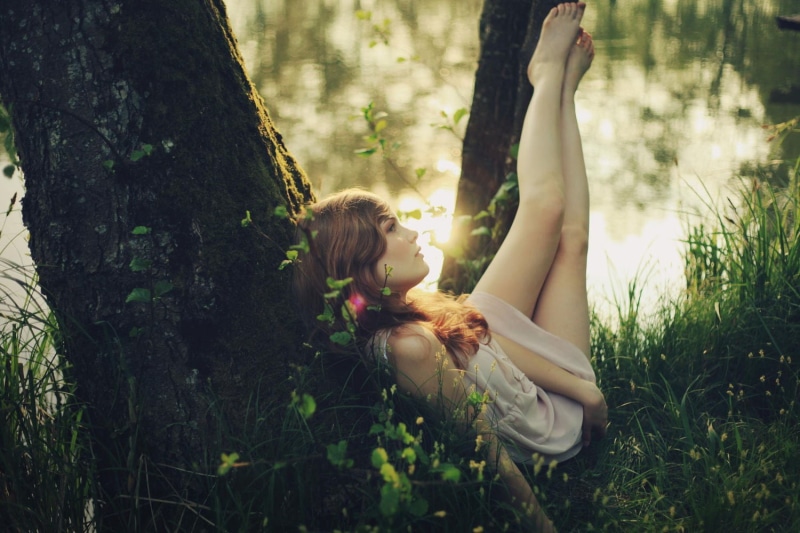 tree trunk, plant, sunlight, trees, looking away, hairstyle, 720P, real people, hair, young women, arms raised, feet in the air, one person, young adult