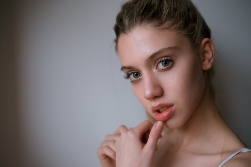 green eyes, beautiful woman, adult, contemplation, gray background, one person, blonde, portrait, hand, human hand, beauty, looking at viewer, indoors