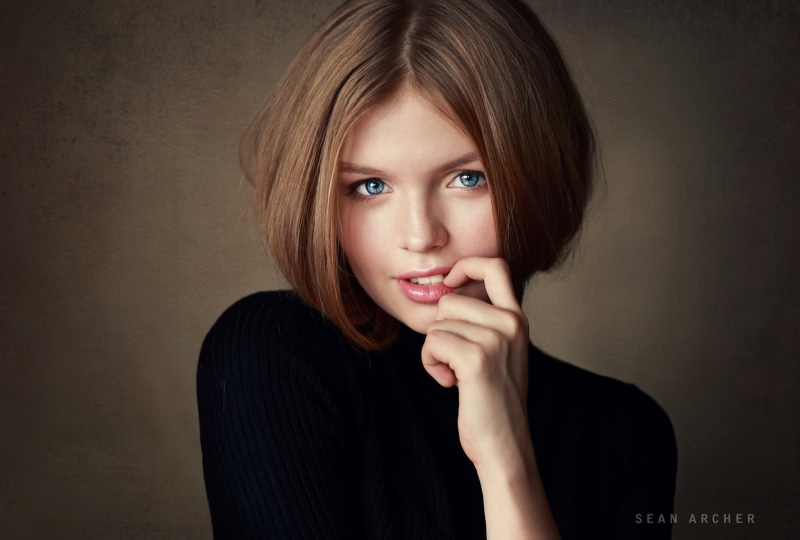 one person, looking at camera, hair, looking at viewer, casual clothing, hand on chin, beauty, short hair, close-up, blue eyes, simple background, indoors