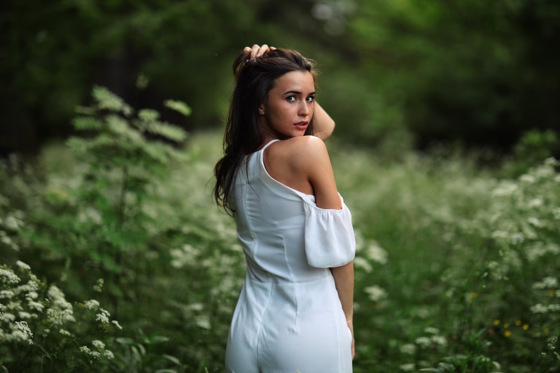 day, looking at viewer, fashion, hairstyle, depth of field, women outdoors, side view, focus on foreground, brunette, model, three quarter length, standing