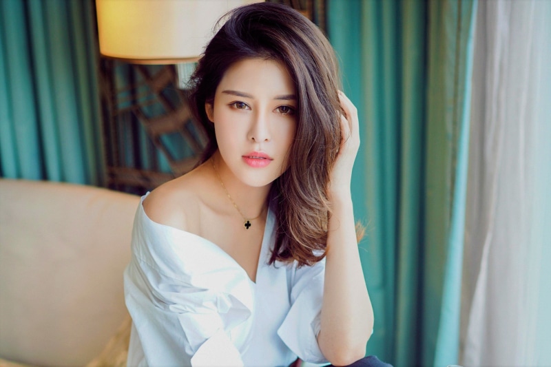 focus on foreground, women, lifestyles, adult, waist up, young adult, hair, casual clothing, standing, Asian, curtain, hazel eyes, fashion, hands in hair