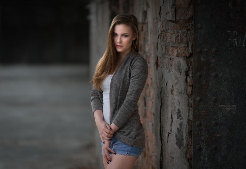 looking at viewer, women, jean shorts, young women, depth of field, hairstyle, focus on foreground, wall, looking at camera, leisure activity, wall - building feature