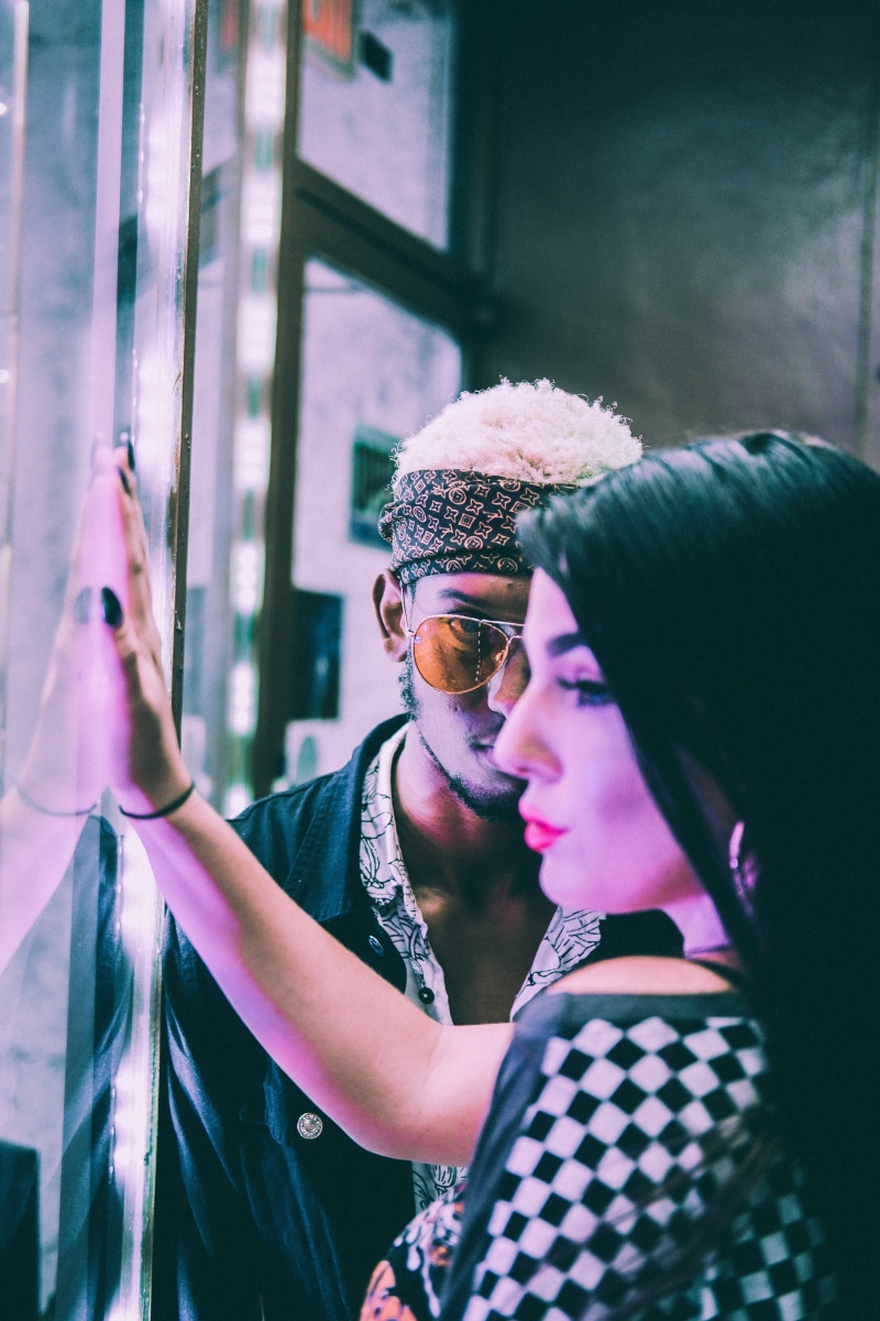 waist up, near, black, headshot, male, real people, wall, women, sunglasses, two people, side view, glass, retrostyle, retro, portrait, facing, shirt, hat