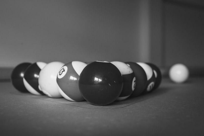 sports equipment, selective focus, cue sports, indoors, pool table, snooker ball, table, pool cue, still life, sphere, billiard table, greyscale, billiard balls