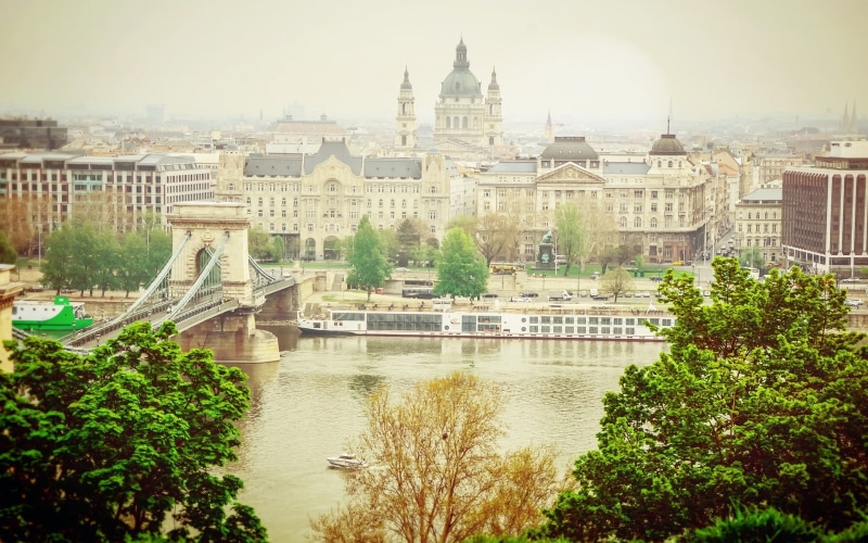 bridge, day, tree, rise, building, sky, river, travel destinations, history, high, plant, building exterior, built structure, water, tourism, white, architecture