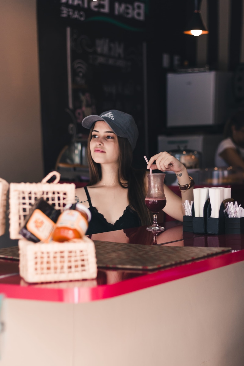 woman, table, women, headshot, sitting, hairstyle, beverage, container, food, business, drink, coffee shop, refreshment, fashion, bistro, glass, adult