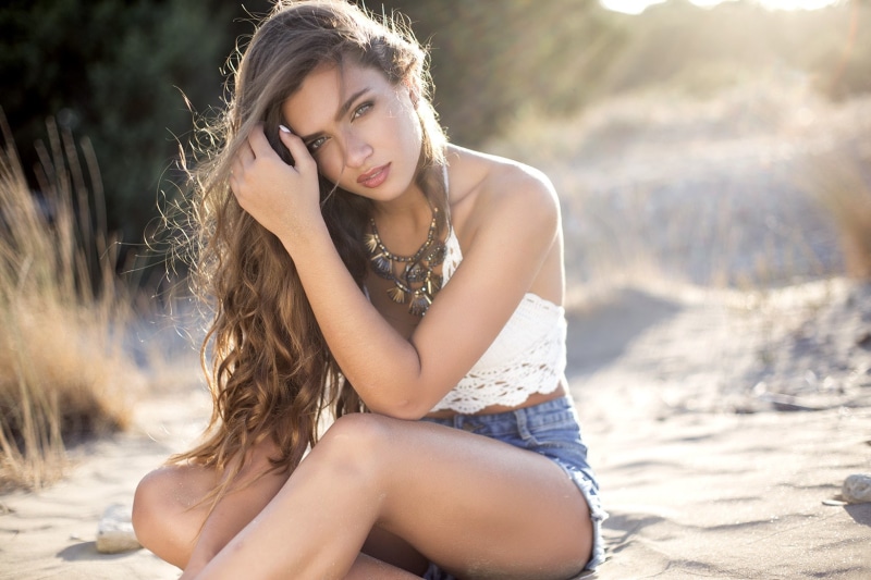 portrait, long hair, focus on foreground, sitting, hairstyle, land, 720P, three quarter length, leisure activity, jean shorts, outdoors, young women, young adult