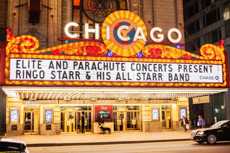 the chicago theatre, town, automobile, car, vehicle, city, train, western script, train station, built structure, outdoors, subway, text, shop, store, communication