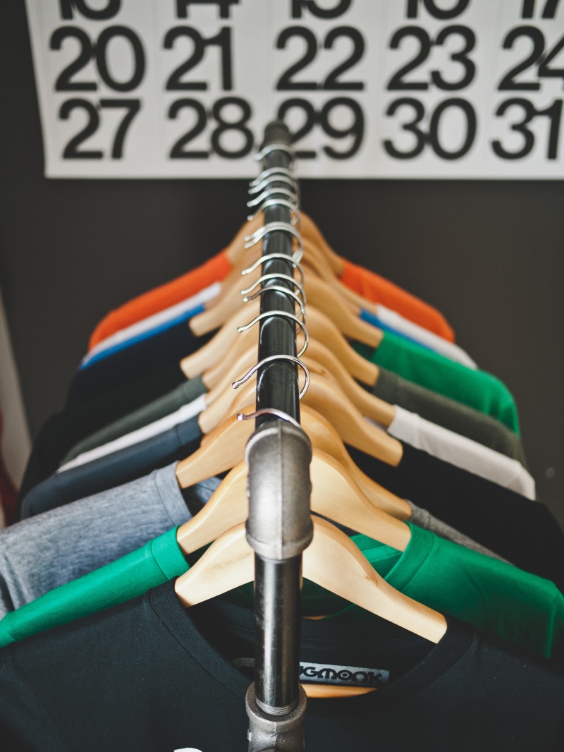clothes, communication, hanged, black color, large group of objects, hanging, indoors, no people, tshirt, coathanger, equipment, metal, order, in a row