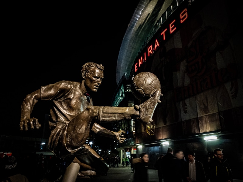 indoors, iphone xs max, football, art, sculpture, people, statue, built structure, ball, 2K, city, communication, playing, text, dennis bergkamp, town