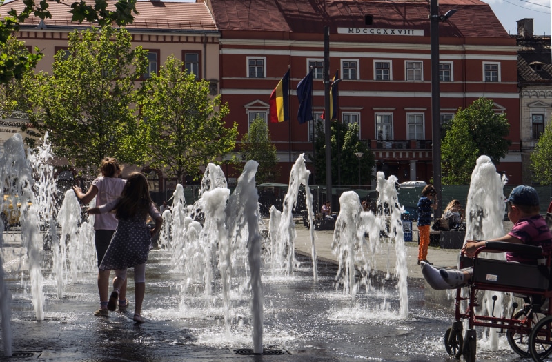 romania, built structure, day, lifestyles, fair, women, city, group of people, fountain, spraying, contrast, tree, real people, building exterior, outdoors