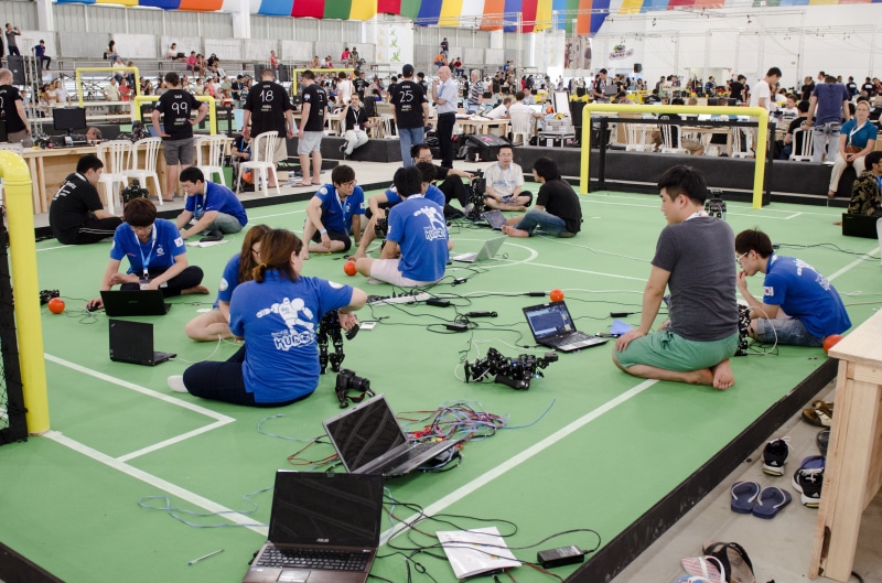 architecture, table, cybernetics, mixed age range, robocup, large group of people, spectator, humanoides, watching, relaxation, future, real people, sitting