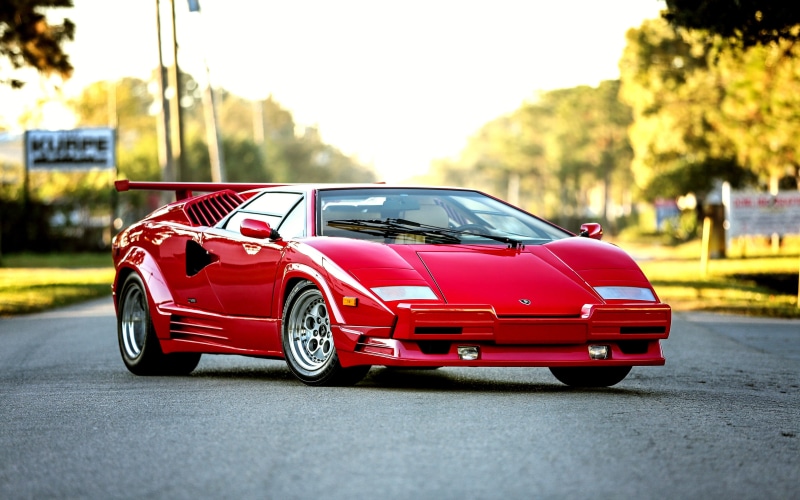street, focus on foreground, mode of transportation, sports car, road, red, Lamborghini Countach, architecture, city, speed, car, land vehicle, motor vehicle
