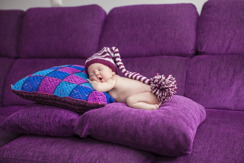 cute, purple, indoors, full length, domestic room, child, sofa, furniture, young, living room, one person, relaxation, pillow, baby, sitting, innocence