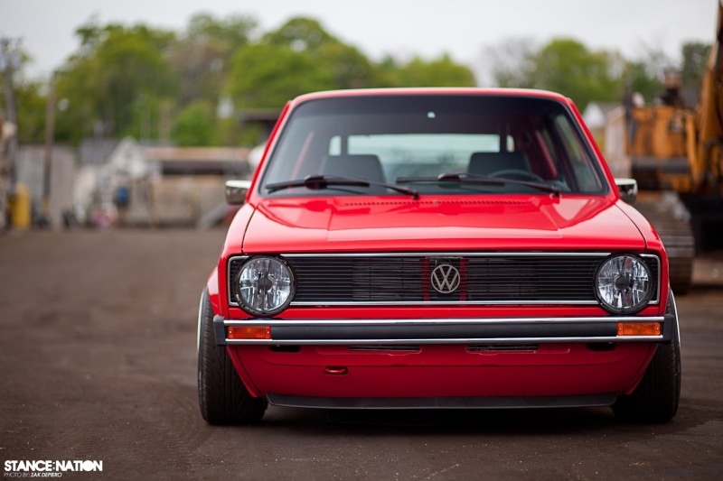 Golf 1, focus on foreground, transportation, red cars, 720P, outdoors, incidental people, retro styled, land vehicle, motor vehicle, road, stationary
