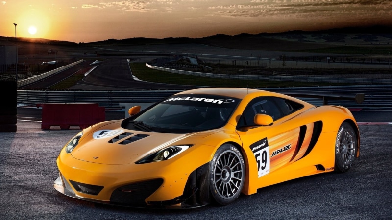 wheel, sports, orange cars, yellow, outdoors, mode of transportation, racecar, road, sport, street, motion, taxi, city, architecture, land vehicle, sunset