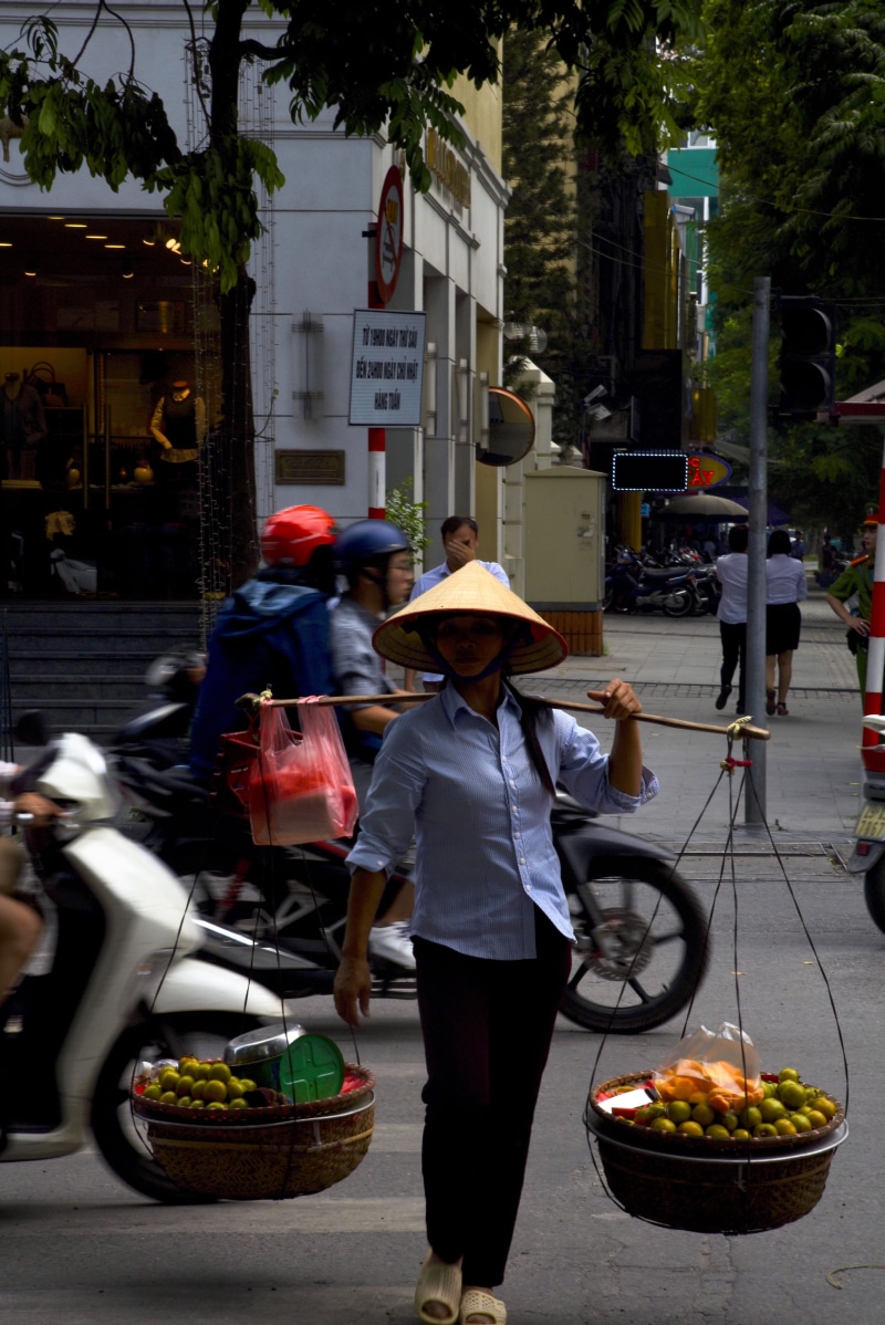 person, asphalt, apparel, hat, architecture, occupation, machine, food and drink, real people, city, footwear, human, women, container, mode of transportation