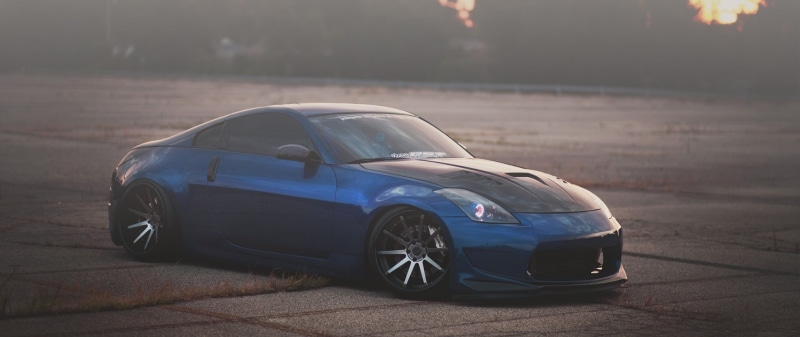outdoors, travel, focus on foreground, street, ultra-wide, sunlight, 2K, headlight, nature, luxury, city, land vehicle, no people, car, Nissan 350Z, day