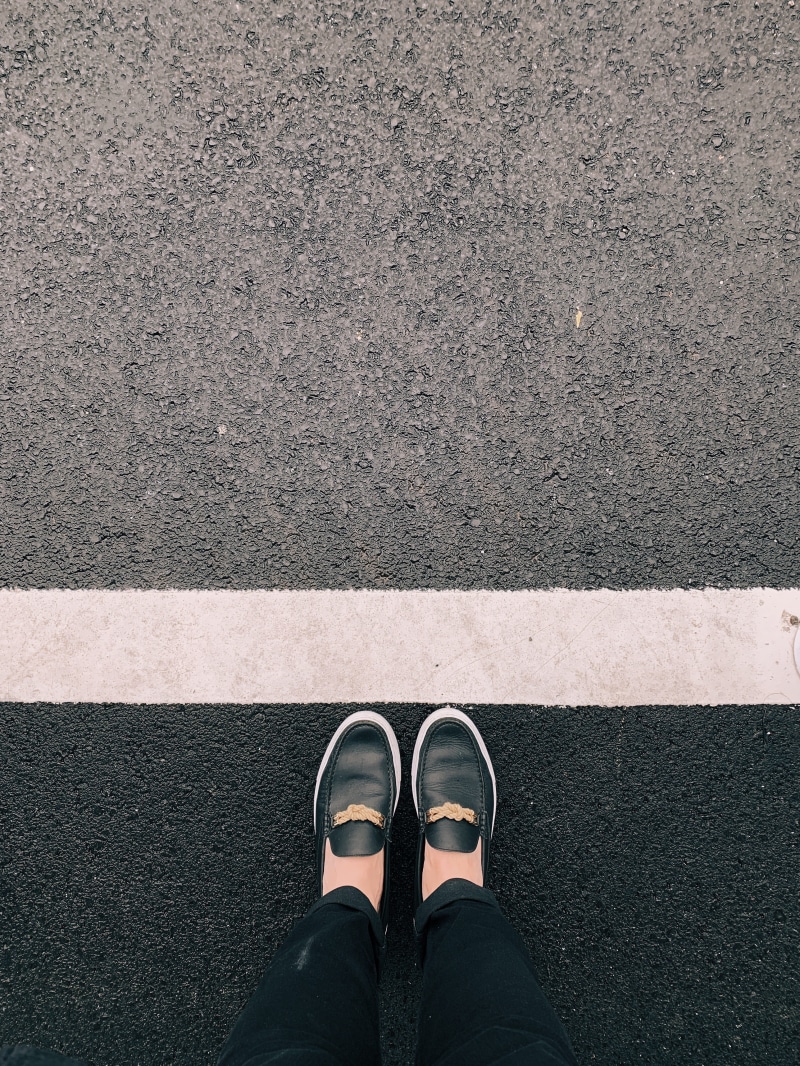 human limb, directly above, asphalt, apparel, person, outdoors, word, shoe, real people, body part, clothing, day, street, low section, denim, one person