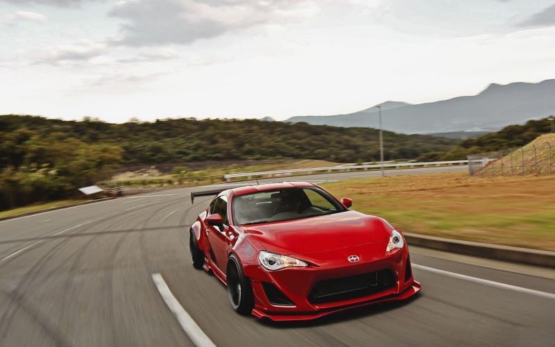 road trip, outdoors, no people, travel, day, road marking, red cars, nature, land vehicle, tree, mode of transportation, road, blurred motion, Scion FR-S