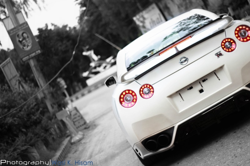 road, luxury, western script, travel, tilt, tree, text, focus on foreground, land vehicle, outdoors, motor vehicle, Nissan Skyline GT-R R35, no people