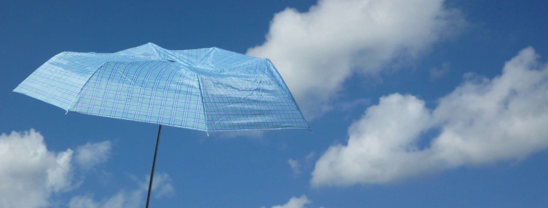 motion, low angle view, outdoors, day, umbrella, wind, parasol, clouds, banner, textile, white color, nature, sky, carelessness, relaxation, mid-air, holiday