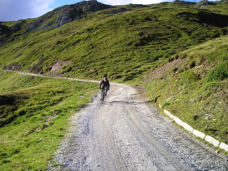 tranquil scene, away, real people, one person, riding, walking, tranquility, mountains, the way forward, tour, grass, bike ride, plant, transportation