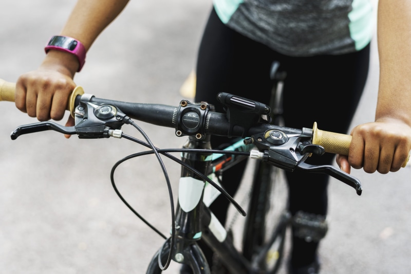 focus on foreground, fitness, holding, biking, human hand, active, equipment, smartwatch, machinery, real people, land vehicle, lifestyle, bike handlebar