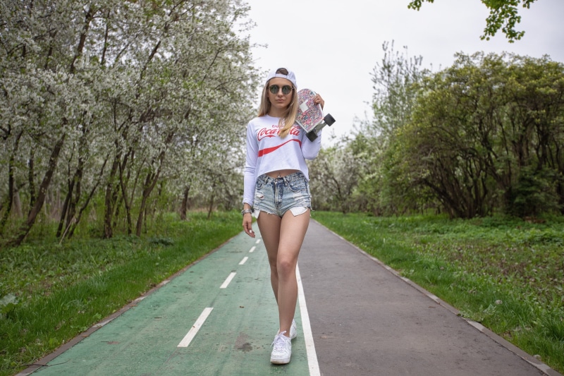 one person, fashion, beautiful woman, lifestyles, women, women outdoors, front view, happiness, full length, white nails, young adult, skateboard, Coca-Cola