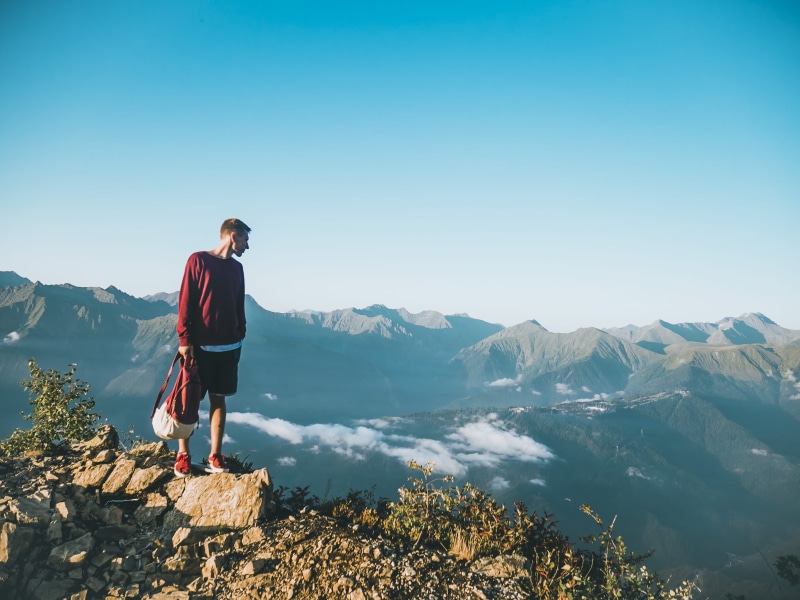 clear sky, leisure activity, casual clothing, beauty in nature, man, mountain range, one person, adventure, tranquil scene, top, rock, standing, view, mountain