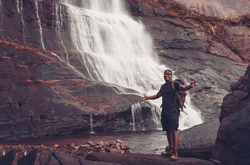 beauty in nature, stones, adventure, long exposure, standing, backpack, mountain hiking, smile, young adult, solid, cascade, rock, flowing, recreation