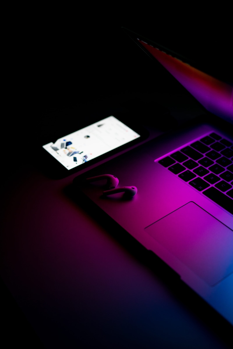 studio shot, 5K, tech product, programmer, laptop, black background, macbook, close-up, keyboard, product shot, airpod, neon purple, purple, smart phone