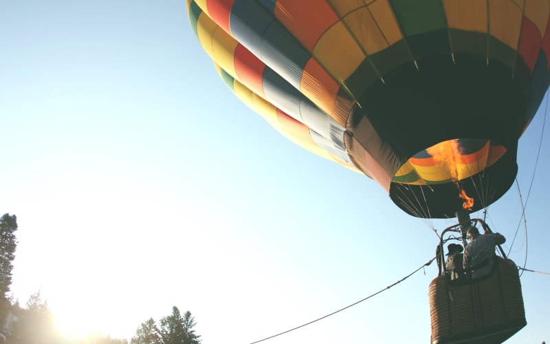 hanging, multi colored, hot, balloon, blue, air vehicle, outdoors, sunlight, sky, hot air balloons, tree, air, day, adventure, multicolored, 2K, low angle view