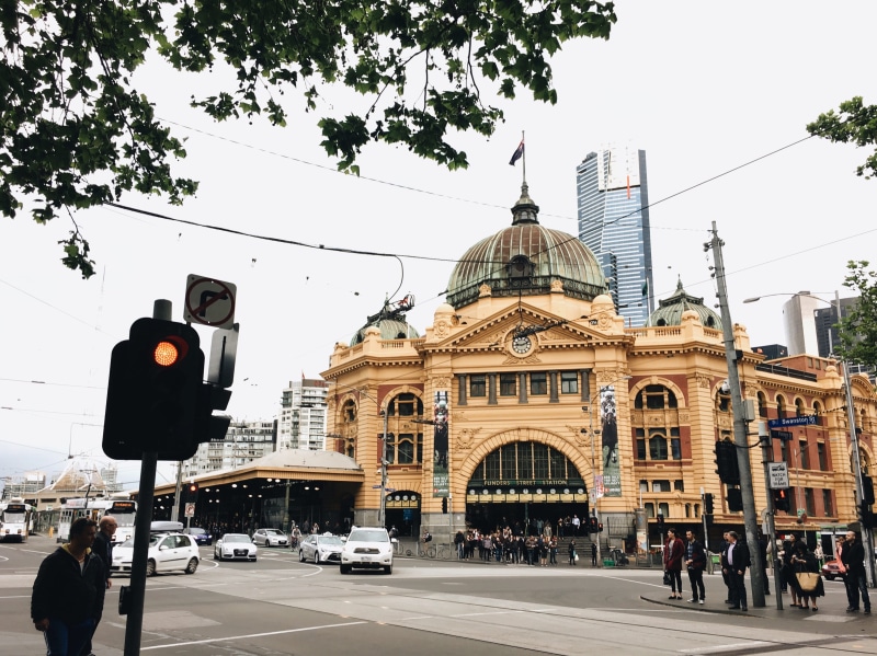 road, car, built structure, street, train station, tree, outdoors, light, stoplight, sky, city, day, transportation, streetscape, travel, flinders street railway station
