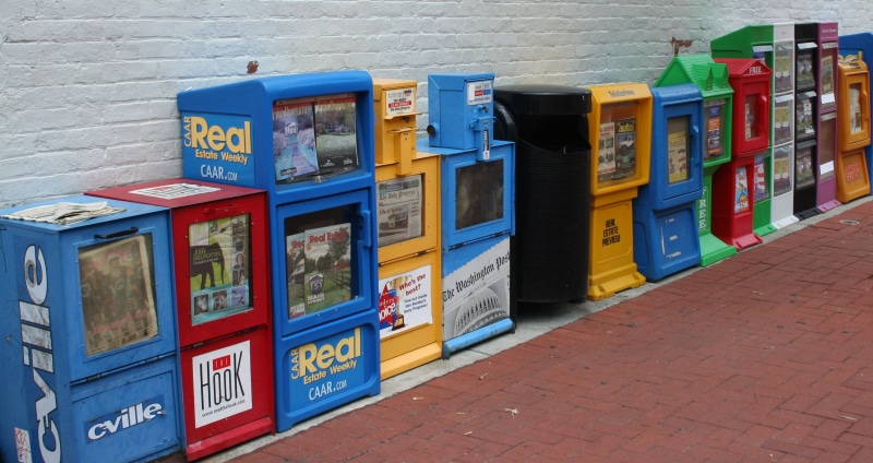 sidewalk, wall, box - container, footpath, side by side, blue, vending machines, no people, brochure, assorted, metal, pamphlets, printed material, text
