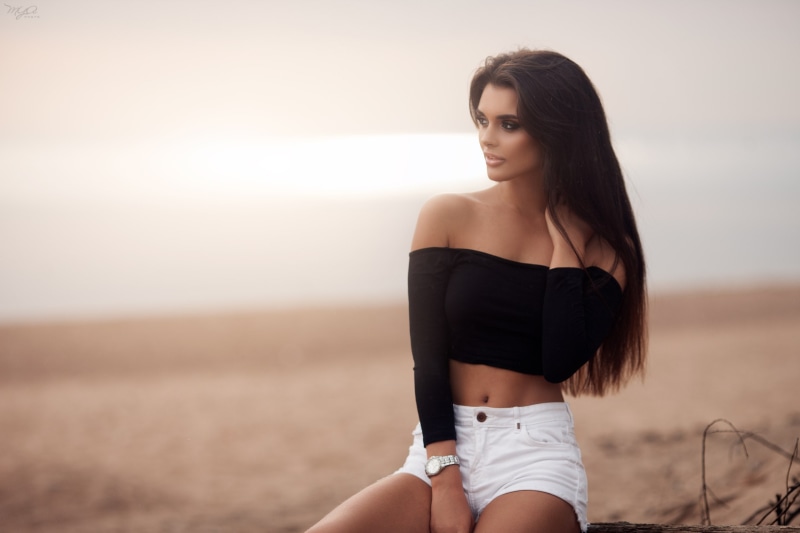 women, sitting, long hair, portrait, 2K, tanned, women outdoors, belly, jean shorts, sand, depth of field, looking away