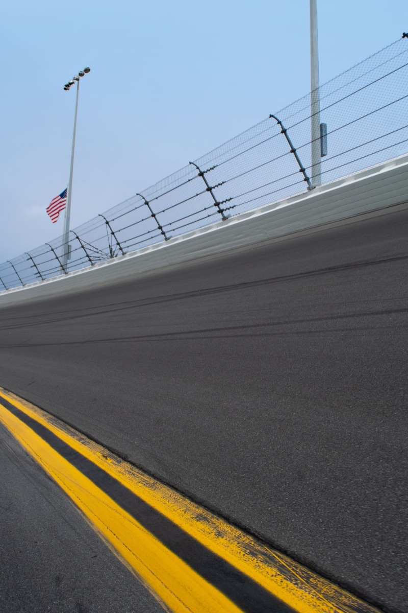 race, speedway, dividing line, motorsports, flag, street, corner, banked, road marking, symbol, venue, road, daytona 500, yellow lines, transportation