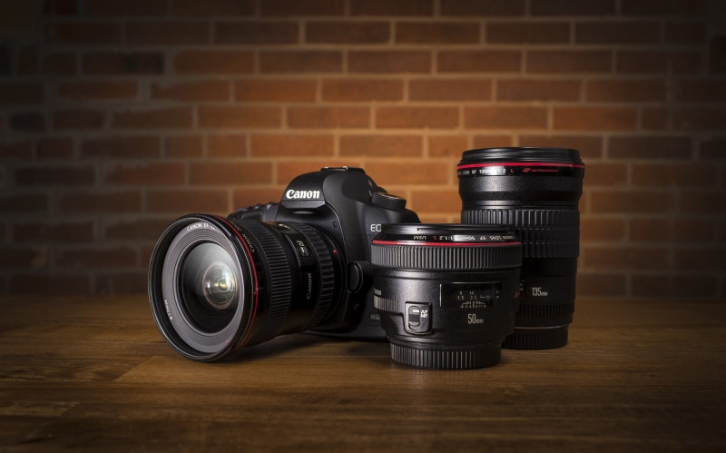 lens, digital camera, black, the camera, silver colored, no people, flooring, lens - eye, wall - building feature, brick, dslr, brick wall, indoors, still life