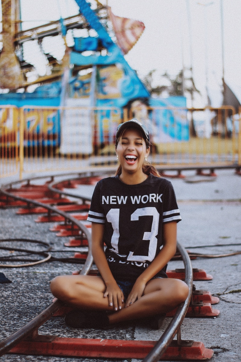 looking at camera, portrait, outdoors, legs crossed, graffiti, women, leisure activity, smiling, lifestyles, real people, adult, architecture, face, women outdoors
