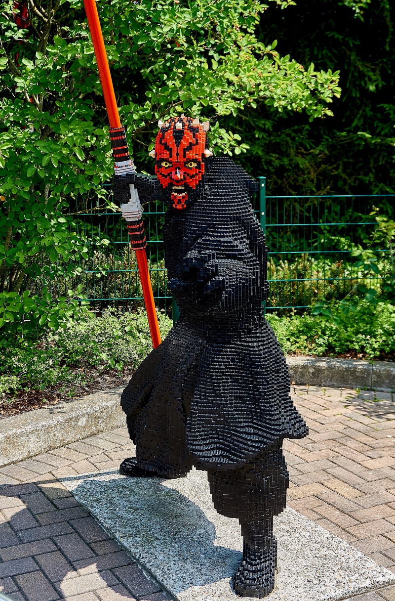laser sword, legoland, outdoors, shrine, sunlight, nature, building blocks, park, lego, male likeness, build, creativity, representation, human representation
