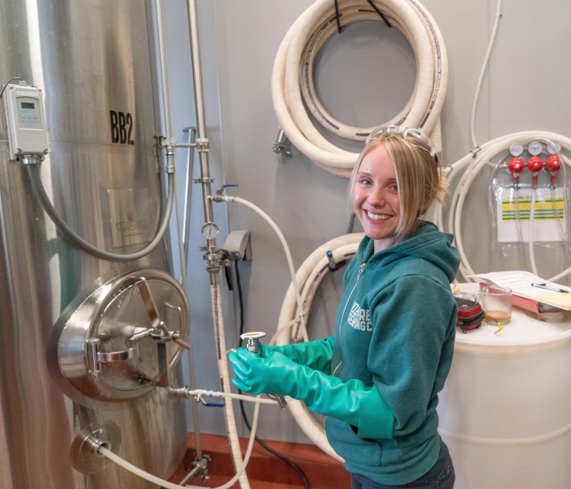 safety, machine, working, rubber, near, looking at camera, barrel, wearing, brewing, wear, women, standing, indoors, beer, industry, stainless steel, casual clothing