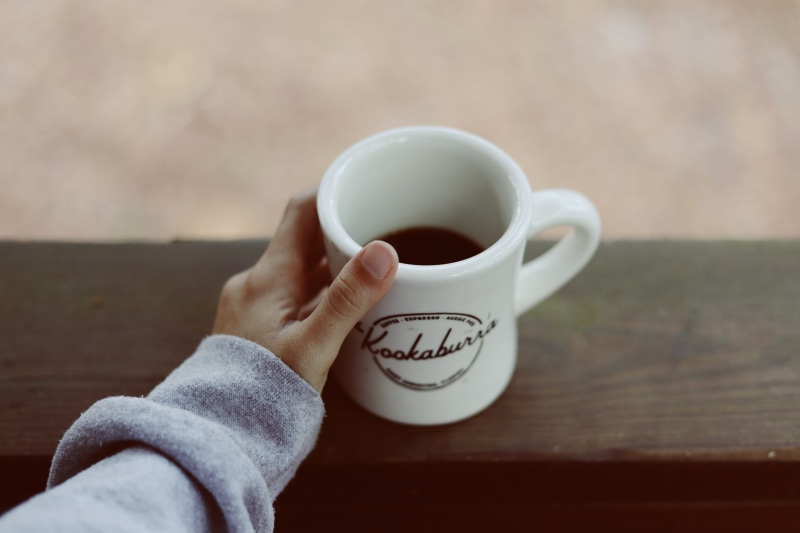human, food and drink, porch, human hand, coffee - drink, latte, person, human body part, mug, beverage, drink, holding, focus on foreground, cup, finger