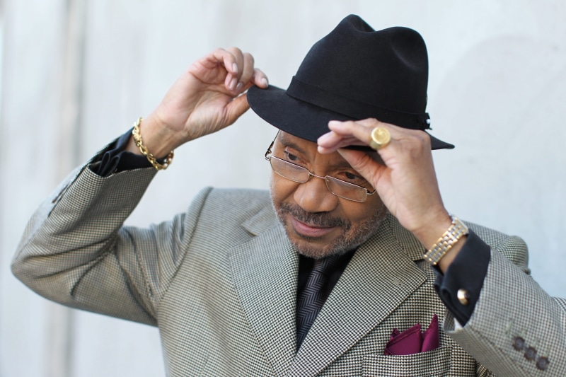 outerwear, facial hair, outfit, facial expression, mature adult, 2K, person, focus on foreground, pose, real people, hands, cap, eyewear, wear, gray, males