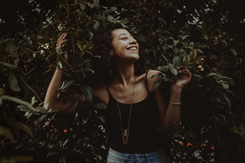 beautiful woman, smiling, plant, lifestyles, leisure activity, hairstyle, closed eyes, standing, casual clothing, young adult, outdoors, waist up, one person