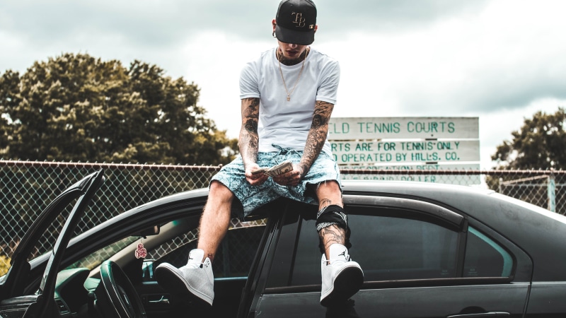 architecture, person, day, bands, tattooed, wad, outdoors, black, money, casual clothing, tattoo, car, transportation, motor vehicle, body adornment, roof