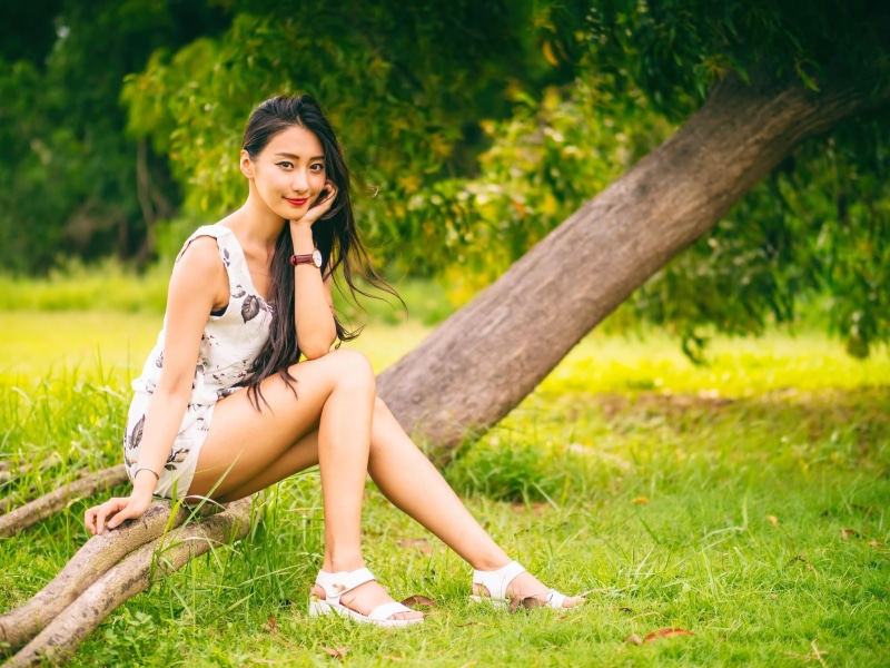 1080P, watch, looking at viewer, hairstyle, Asian, full length, sandals, lifestyles, red lipstick, looking at camera, sitting, outdoors, land, tree, depth of field