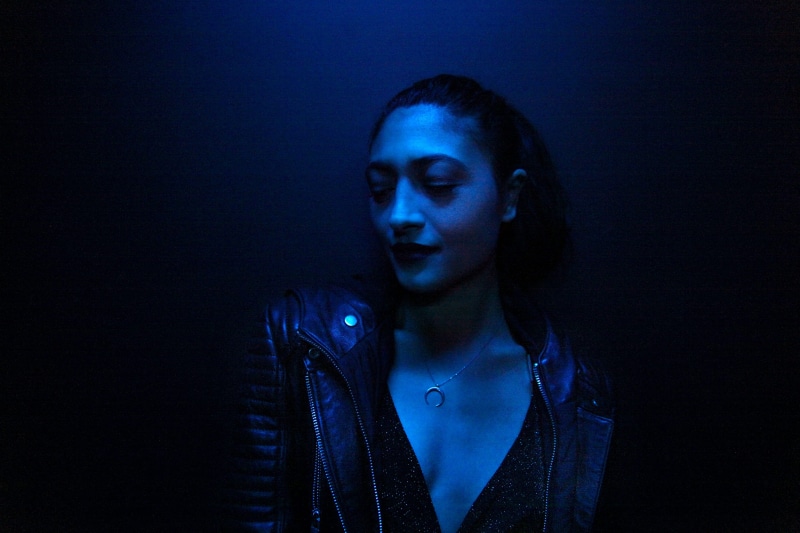 adult, lights, studio shot, black background, portrait, blue neon colour, neon light, looking, hairstyle, women, wearing, black, blue, leaning, wall, beautiful woman